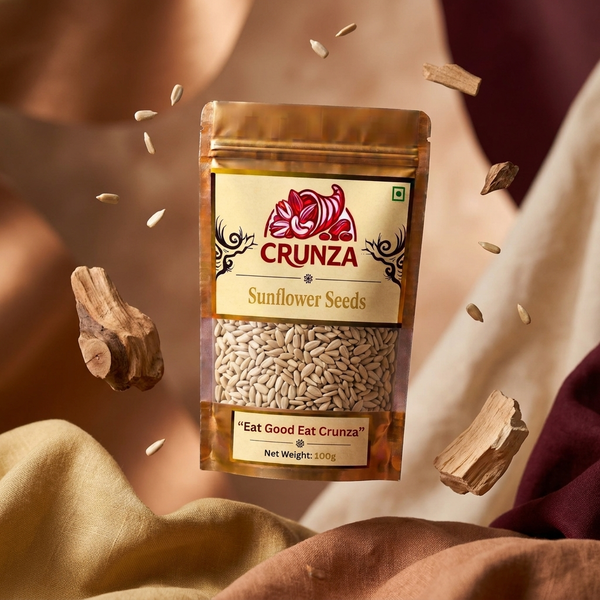 A 100g bag of CRUNZA Sunflower Seeds floating in mid-air, surrounded by scattered seeds and pieces of wood, set against a warm, draped fabric background.