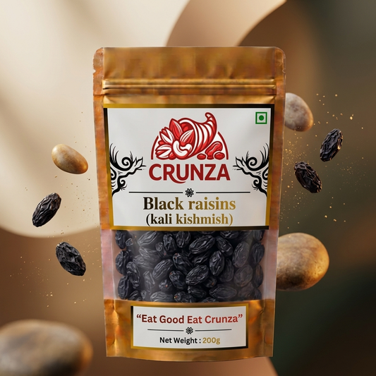 A stand-up pouch of CRUNZA Black raisins (kali kishmish) with floating black raisins and whole stones against a warm beige background.