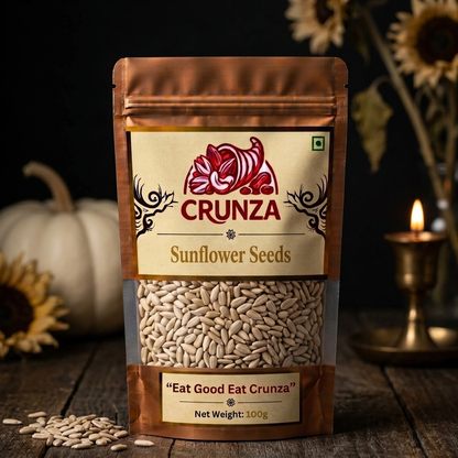 A 100g stand-up pouch of CRUNZA sunflower seeds on a rustic wooden surface, with sunflower seeds scattered in front, a white pumpkin on the left, and a brass candle holder with a lit flame on the right against a dark background.