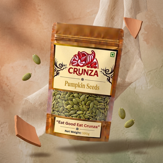 A stand-up pouch of CRUNZA pumpkin seeds with a clear window showing green seeds inside, set against a warm beige textured background with floating loose seeds and decorative broken tile fragments.